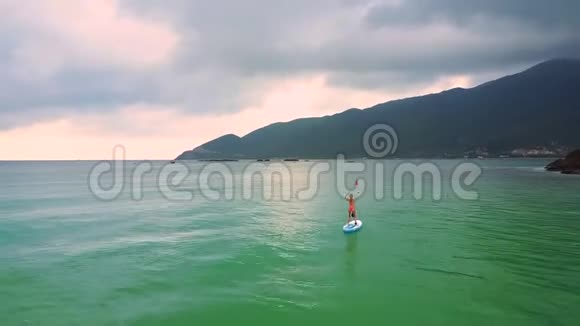 船帆上的女孩沿着海岸泡沫般的波浪在沙滩上翻滚视频的预览图