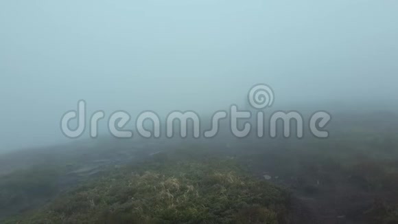 孤独的人漫步在一条丘陵的道路上在一个寒冷的刮风的日子里爬山风吹云雾是莫的视频的预览图