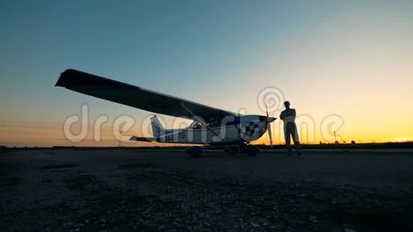 日落时分雄飞行员和他的小型飞机在跑道降落视频的预览图