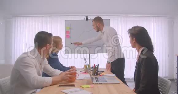 四个大联盟在办公室室内开会的肖像商人在白板上画一张图表视频的预览图