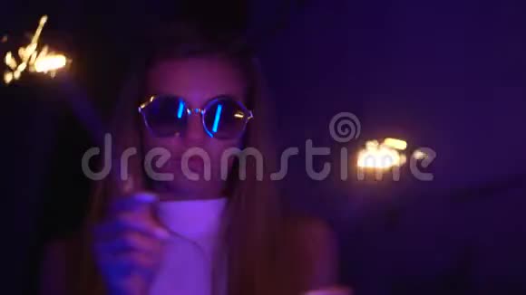 一个年轻漂亮的女孩晚上在城市的霓虹灯附近戴眼镜和漂亮镜片的嬉皮士少年视频的预览图