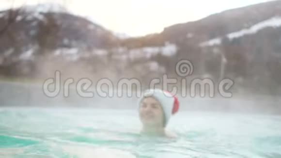 冬天穿帽子和泳衣的女人在炎热的室外游泳池里游泳山里的温泉寒假视频的预览图