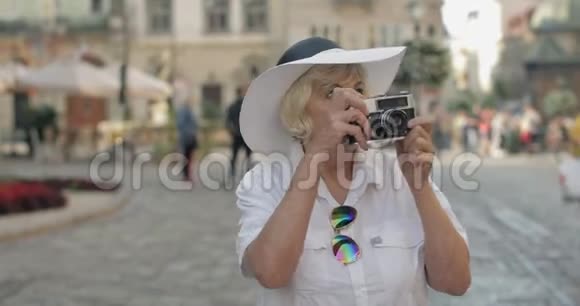 高级女游客探索小镇用复古相机拍照视频的预览图