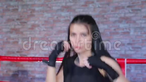 特写可爱的黑发女孩站在拳击架上双手裹着黑色运动绷带靠在脸上练习拳击视频的预览图