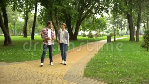 40多岁的父亲和儿子在公园散步分享他的生活经验和技巧视频的预览图