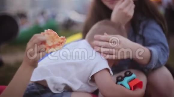 夏天两个女孩和小男孩在公园玩得很开心女孩吃披萨男孩玩玩具车视频的预览图
