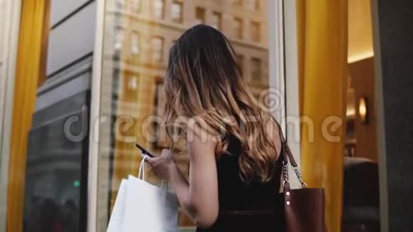 镜头跟随年轻女性美妆博主拎着购物袋双手走在街头慢动作视频的预览图