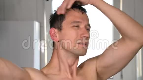 无衫青年用吹风机吹干头发看镜子视频的预览图