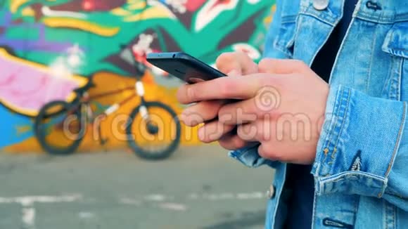 用一部带有自行车的智能手机和背景上的涂鸦来拉近男性的双手视频的预览图