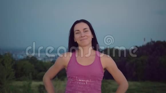城市背景上一位迷人的年轻女子的肖像穿紫色t恤的女运动员展示她的运动衫视频的预览图