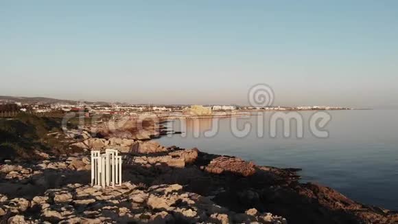 日落时在岩石海滩上用白色纪念碑俯瞰帕福斯市塞浦路斯性质视频的预览图