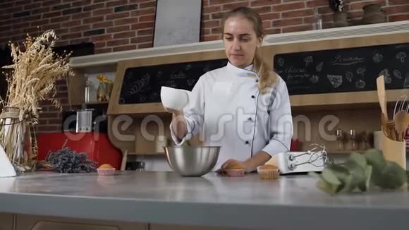 年轻的女性糖果师在碗中倒入白色蛋奶油用于涂抹酸奶油视频的预览图