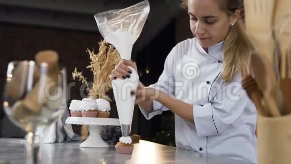 年轻糖果师用糕点包在蛋糕上放奶油的多利镜头视频的预览图