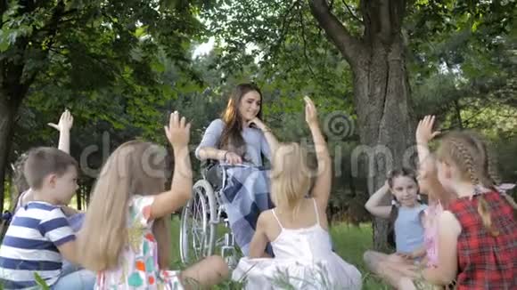 残疾青年教师在公园为男孩和女孩读书视频的预览图