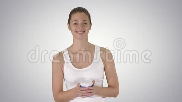年轻漂亮的女人带着咖啡微笑着在梯度背景下行走视频的预览图