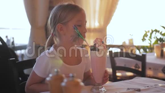可爱的小女孩在咖啡馆里吃奶昔和甜点视频的预览图