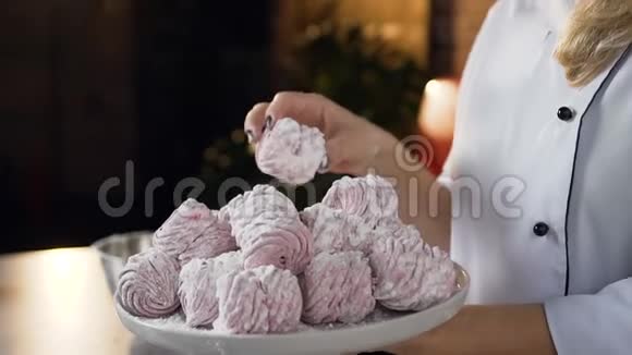 从盘子里取出棉花糖的母面包师手的特写镜头视频的预览图