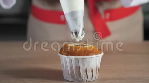 糕点厨师装饰松饼在纸杯白色奶油与糕点袋视频的预览图