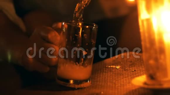 夏季夜晚海滩酒廊用蜡烛将一杯泡沫汽水倒入桌上的玻璃杯中拍摄特写镜头视频的预览图