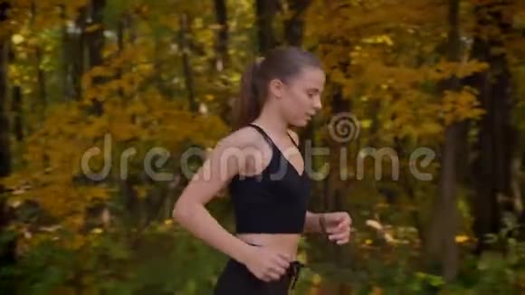 多莉拍摄的年轻苗条女孩穿着连衣裙谁去秋天公园慢跑视频的预览图