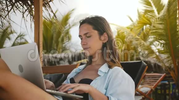 美丽专注的高加索工作狂商人在笔记本电脑移动办公室工作在异国情调的海滩椅子度假视频的预览图