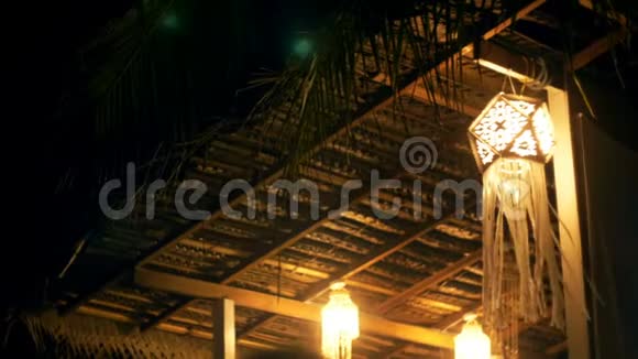 大气背景拍摄的夜晚露台上美丽的弦灯传统的纸灯笼在风中挥动视频的预览图