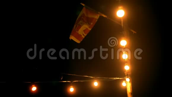 美丽的背景拍摄大气的夜晚露台户外弦灯斯里兰卡的大旗在轻风中挥舞视频的预览图