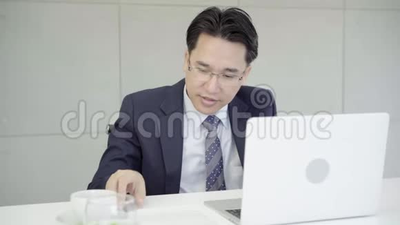 慢动作亚洲商人在办公室工作桌上有笔记本电脑和文件顾问律师概念视频的预览图