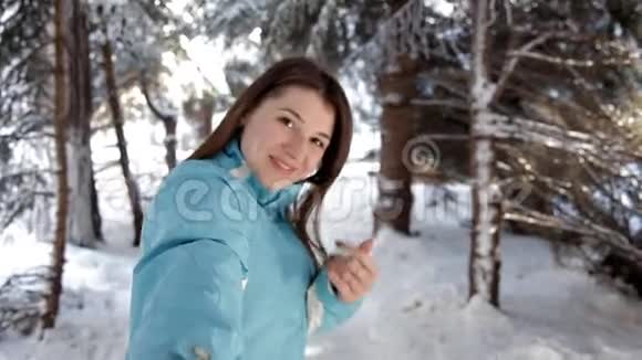 美丽的女人在冬天的森林里的雪树间散步享受第一场雪视频的预览图