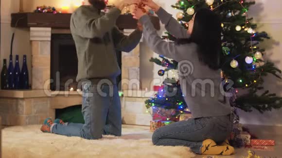 有趣的情侣在家装饰圣诞树快乐的一对夫妇准备圣诞晚会居家休闲理念视频的预览图