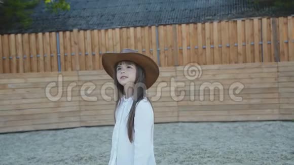 戴帽子的可爱的小女孩来抚摸黑马的头视频的预览图