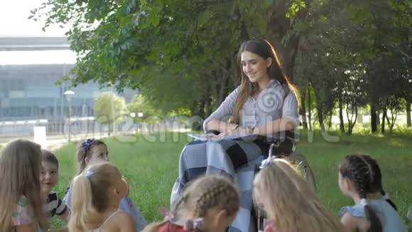 残疾青年教师在公园为男孩和女孩读书视频的预览图