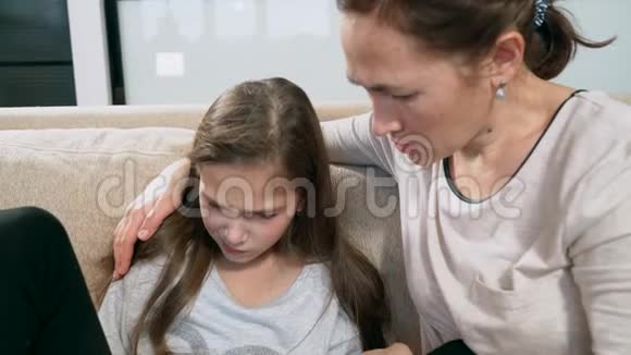 心烦意乱的小女孩坐在沙发上拥抱她的妈妈视频的预览图