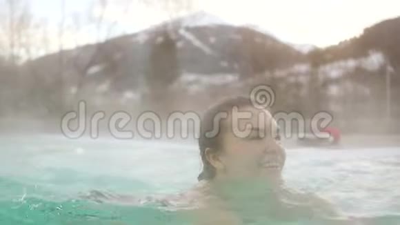 年轻女子在冬天的露天温泉里游泳一个深色头发的女人和寒冷的游泳池的肖像视频的预览图