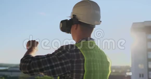 日落时分建筑屋顶上的建筑工程师站在vr眼镜里用vr的接口移动他的手视频的预览图