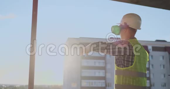 建筑工程师在日落时站在屋顶上戴着VR眼镜用它的界面移动双手视频的预览图