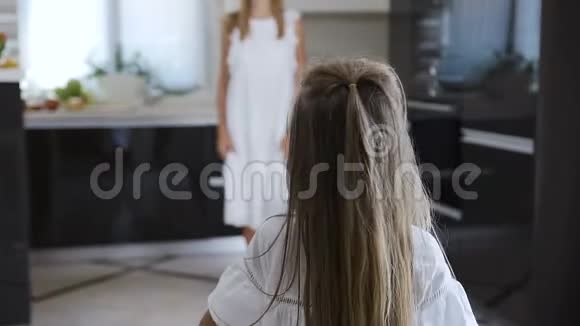 孩子跑进姐姐的手拥抱她两个女孩穿着白色连衣裙小女孩很高兴再次在视频的预览图