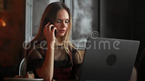 女人手拿着白色手机在桌子上办公室里有一台笔记本电脑视频的预览图