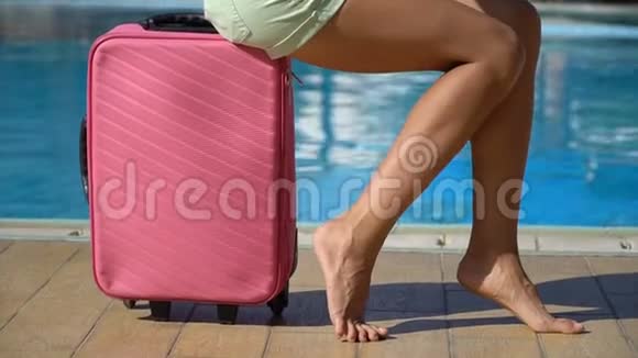 酒店游泳池附近带粉红色箱子的年轻女子旅行度假概念视频的预览图