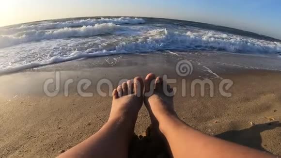 女孩坐在海边海浪在沙滩上翻滚视频的预览图