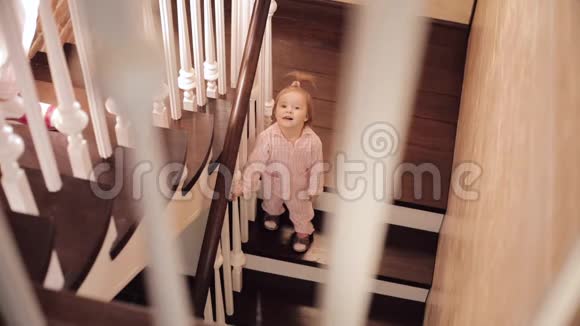 穿粉色睡衣的小女孩坐在楼梯上玩视频的预览图