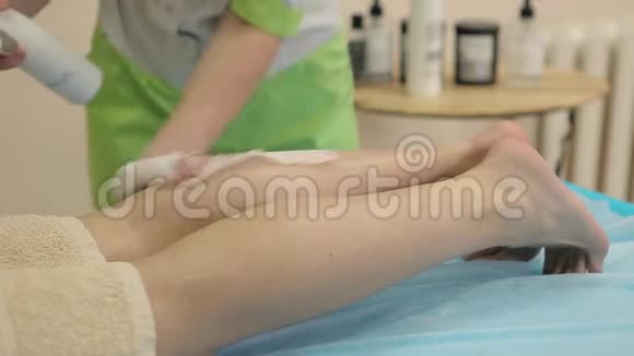 美容师在水疗沙龙脱毛后滋润女性腿部视频的预览图