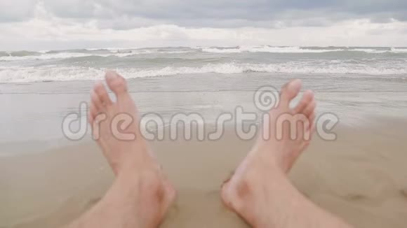 人们在海滩上脚特写看一看海水涌到岸边暑假假期视频的预览图