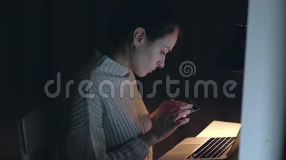 女性晚上在家用笔记本用信用卡购物视频的预览图