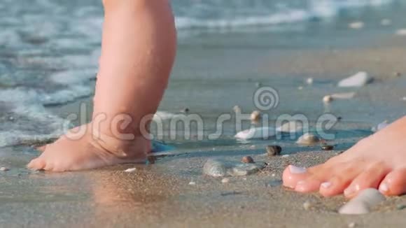 妈妈和宝宝的脚在沙滩上散步刚出生的孩子在海滩上视频的预览图