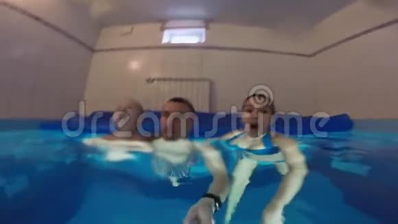 一家人正在游泳池里游泳成功的关节浸入水中一起快乐地在水下游泳视频的预览图