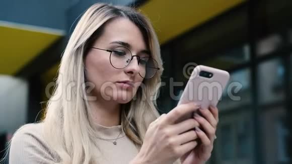 戴眼镜的女人在街上散步时用手机发短信给男朋友关门市区女孩使用视频的预览图