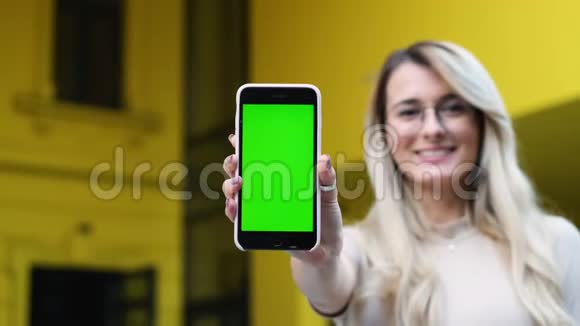 漂亮的年轻女人展示智能手机带有彩色钥匙绿色屏幕使用智能手机的美女视频的预览图