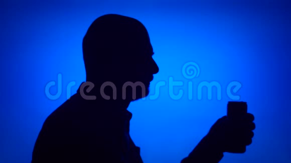 老人打开蓝色背景啤酒罐的剪影喝苏打水的男人脸视频的预览图