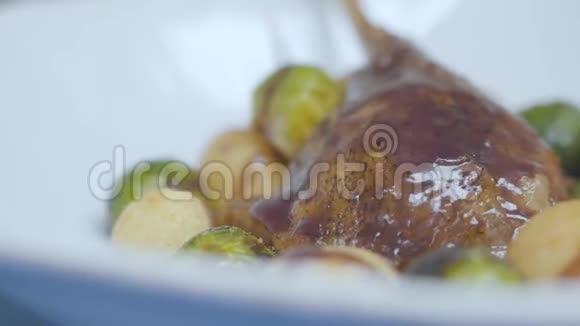 把美味的鸭肉和酱汁放在盘子上上面放着刚烤好的布鲁塞尔芽和奶酪球视频的预览图